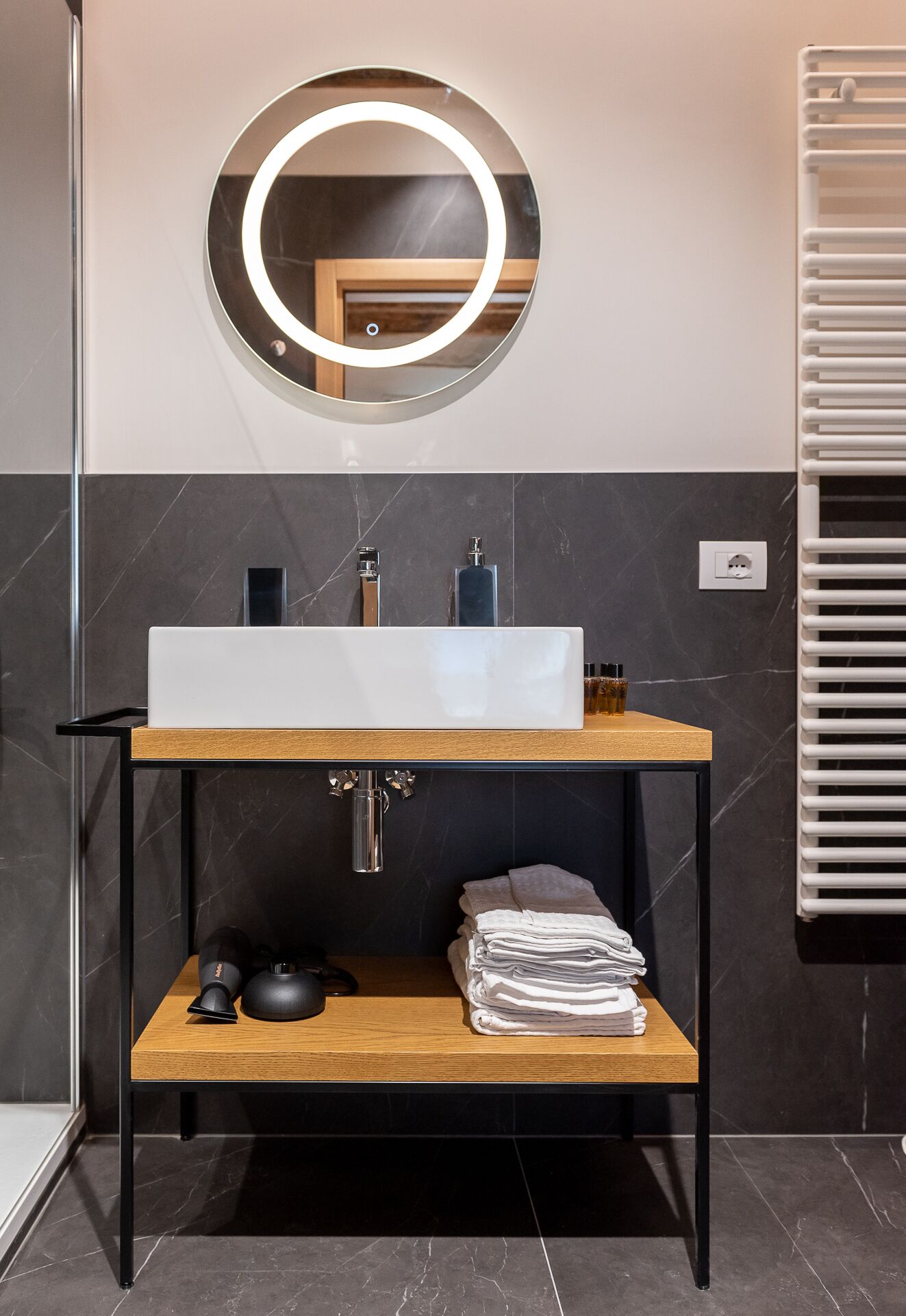 A modern bathroom with a large mirror, a white sink, and a towel rack.