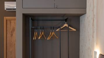 A bedroom with a built-in wardrobe, wooden bench, and hanging clothes rack.