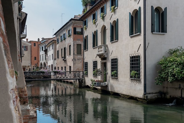 Un canal étroit, bordé de bâtiments des deux côtés, avec des fenêtres en arc de cercle et des balcons ornés de plantes.