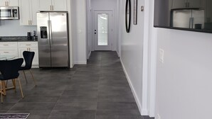 Een moderne keuken met witte kasten, roestvrijstalen apparatuur en een donkere tegelvloer.