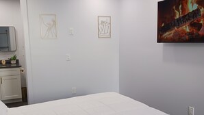 Een slaapkamer met een groot bed, een flatscreen televisie en kunstwerken aan de muur.