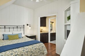 A bedroom with a bed, bedside table, and a nightstand. There is a doorway leading to a bathroom with a sink and mirror. - The Savannah: 2BR + Loft Townhome Sleeps 8 | Pool, Hot Tub, Free Golf, Near Lake Michigan (Holland)