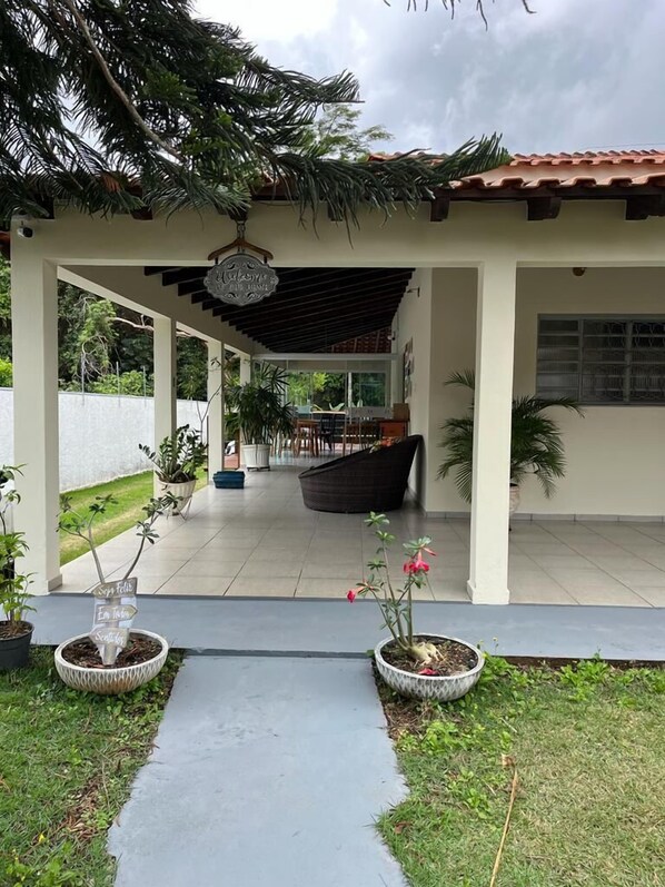A covered patio area with potted plants and a pathway leading to a building. - POUSADA ACONCHEGO MT (Chapada dos Guimarães)