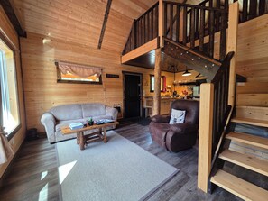 Un intérieur en bois avec un canapé, un fauteuil et un escalier.