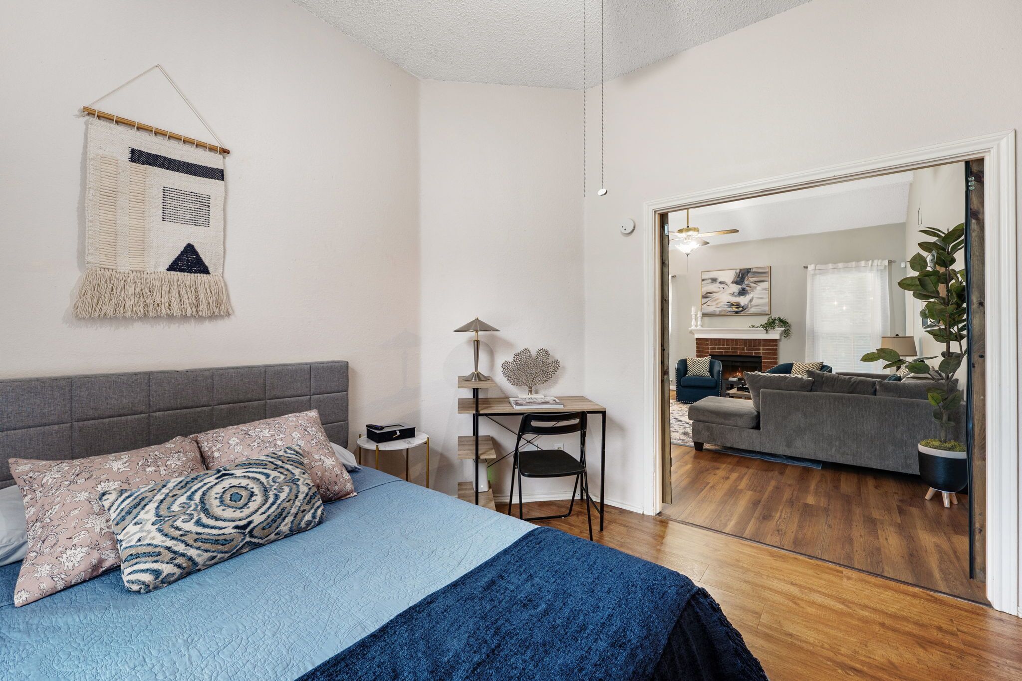 Een slaapkamer met een bed, nachtkastje, lamp en een wanddecoratie.