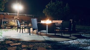 Uma área de estar ao ar livre com lareira, assentos e um poste de luz.