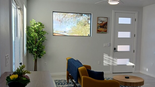 Un saló modern amb zona de menjador, ventilador de sostre, finestra gran i televisió penjada.