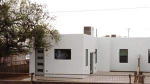 Un edifici modern amb façana blanca, portes numerades i un pati tancat per una tanca.