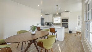 Una cucina moderna con mobili bianchi, un'isola centrale e un'area pranzo con un tavolo rotondo e sedie.