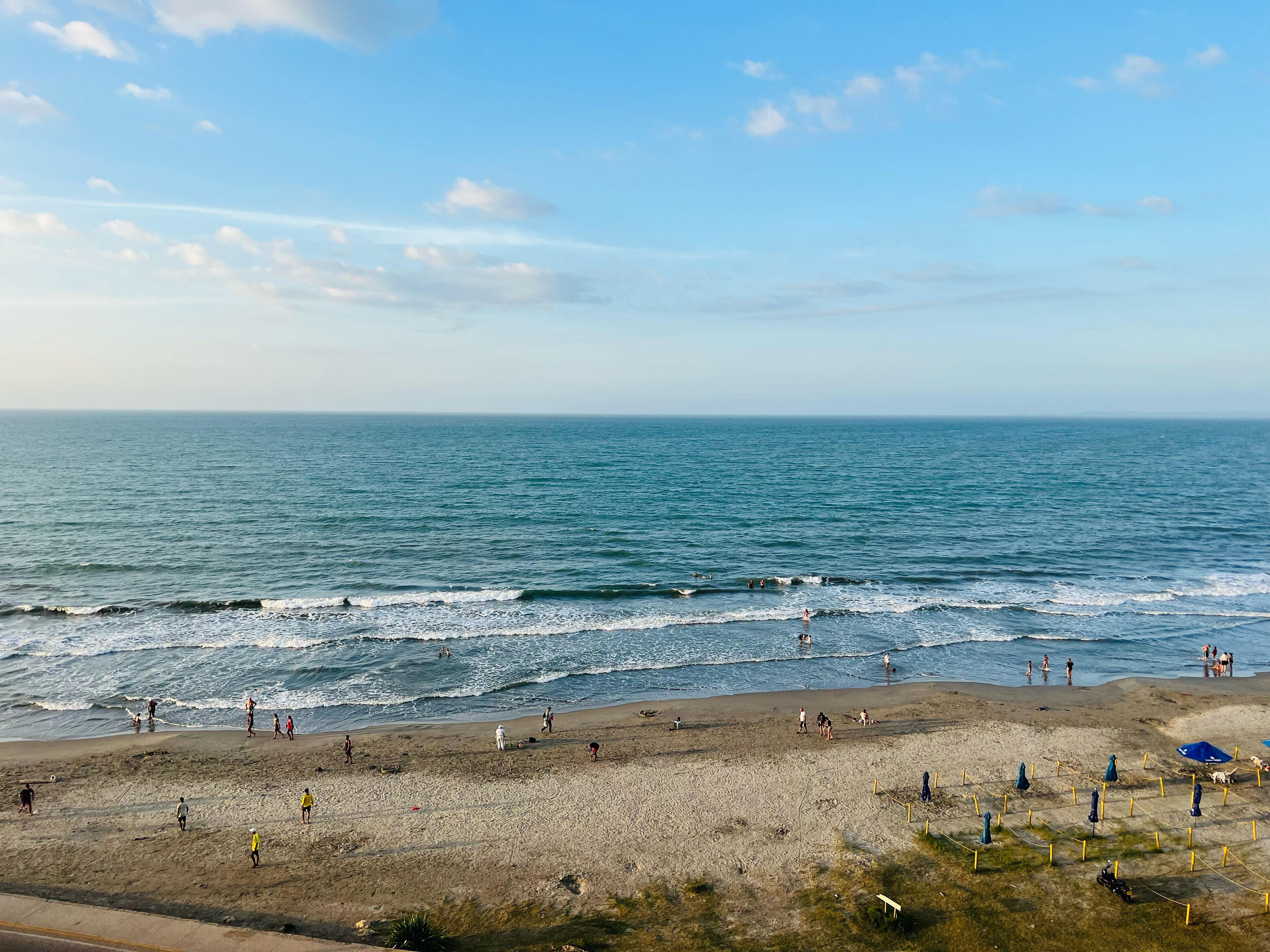 A beach with people walking and playing, a sandy shore, and the ocean.