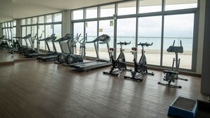 A gym with cardio machines and a large window overlooking the beach. - Apartamento frente al mar Cartagena (Cartagena)
