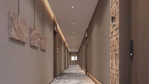 A long, narrow hallway with a patterned wall on the left and a brick wall on the right. - Greater Khingan Tahe Chengxin Business Hotel (Tahe)