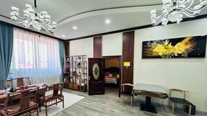 A hotel room with a wooden dining set, a chandelier, a painting, and a door leading to another room. - Greater Khingan Tahe Chengxin Business Hotel (Tahe)