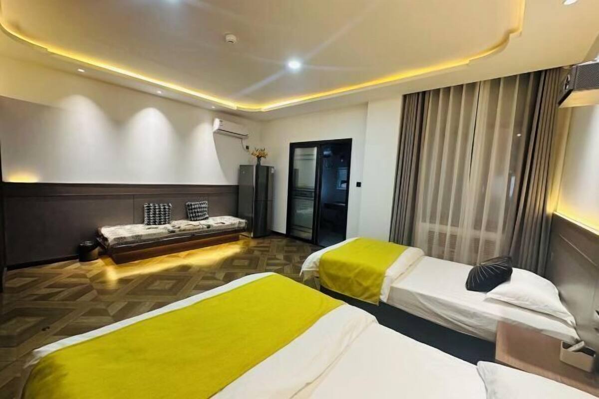 Habitación de hotel con dos camas, un sofá, un escritorio y un espejo.