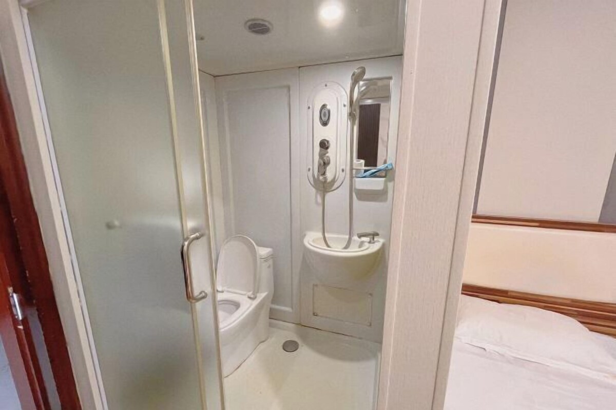 A small, enclosed bathroom with a toilet, sink, and mirror.