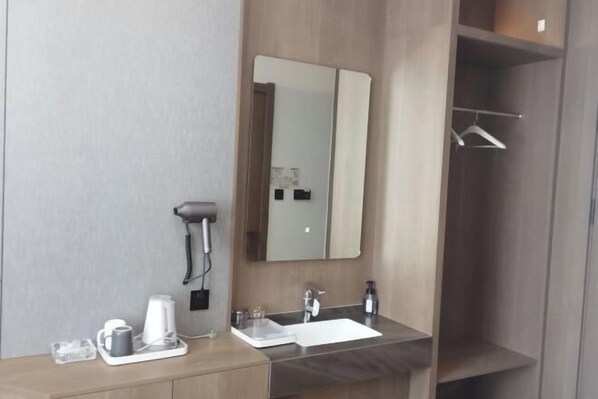 A modern bathroom with a large mirror, a sink, a hairdryer, and a towel rack. - Greater Khingan Tahe Chengxin Business Hotel (Tahe)