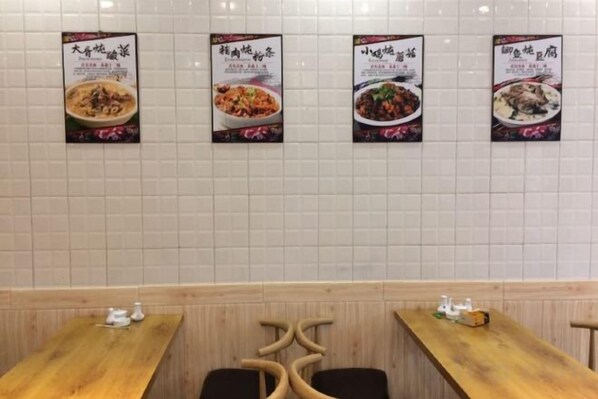 A restaurant interior with tiled walls, wooden tables, and posters of dishes.