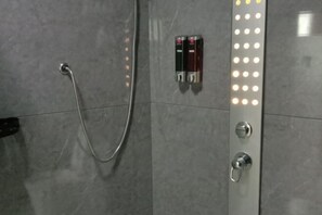 A shower area with a handheld showerhead, a wall-mounted control panel with two bottles, and a series of lights. - Greater Khingan Tahe Chengxin Business Hotel (Tahe)