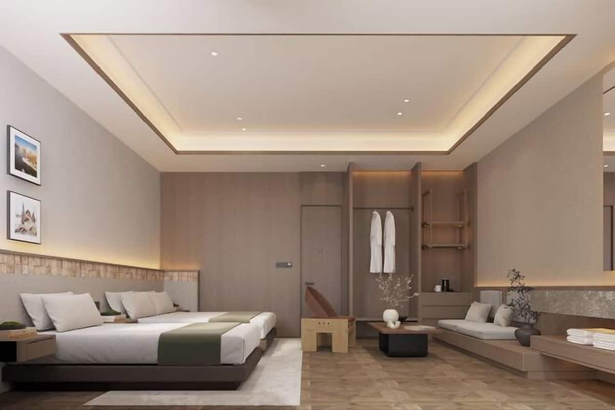 Una habitación de hotel moderna con una cama grande, un sofá, una mesita y un espejo.
