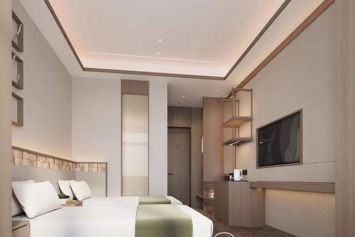 Una habitación de hotel moderna con una cama grande, un televisor montado en la pared y una pequeña zona de kitchenette.