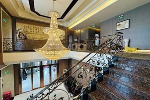 Una imponente escalera con barandales de metal ornamentados y un gran candelabro.