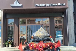 Integrity Business -hotellin sisäänkäynti, jonka edessä on kukkasin ja lipuin koristeltu auto.