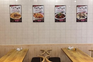 A restaurant interior with tiled walls, wooden tables, and posters of dishes. - Greater Khingan Tahe Chengxin Business Hotel (Tahe)