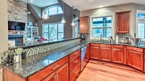 A spacious kitchen with a large island, wooden cabinets, and a stone backsplash. - Lake Access: Waleska House w/ Floating Dock! (Waleska)