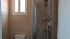 Kylpyhuoneessa on lasiseinällä varustettu suihku, wc ja ikkuna wc:n yläpuolella.