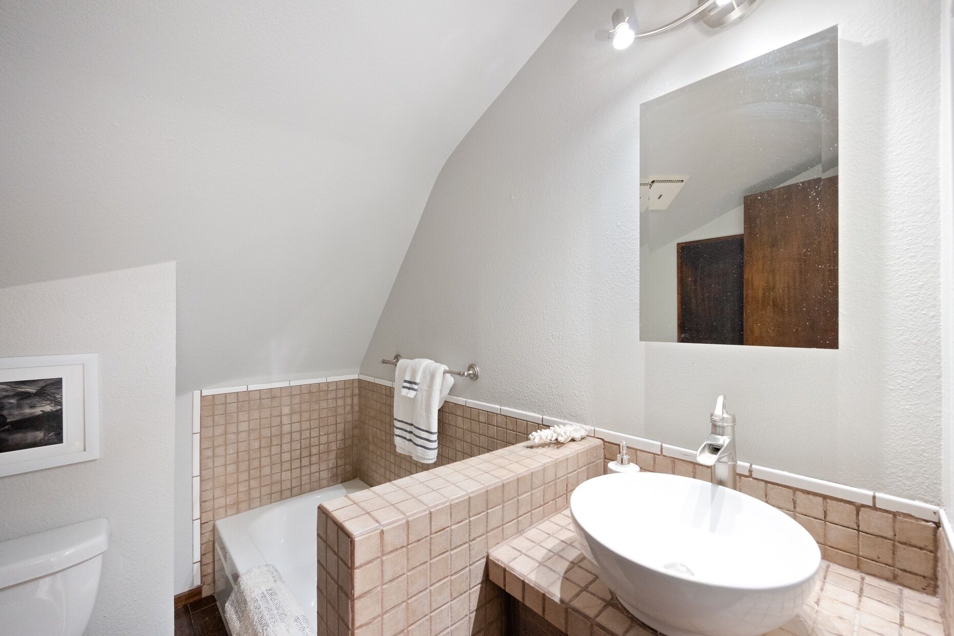 A bathroom with a white sink, a mirror, and a towel rack.