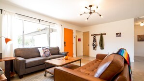 A modern living room with a sofa, coffee table, and a large window. - The Rockhopper - Hot Tub, Fire Pit & Walk To Downtown Jt! 4 Bedroom Home by RedAwning (Joshua Tree)