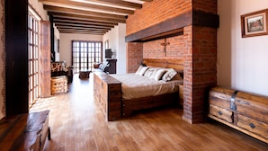 Une chambre avec un lit en bois, une cheminée en briques et une commode en bois.