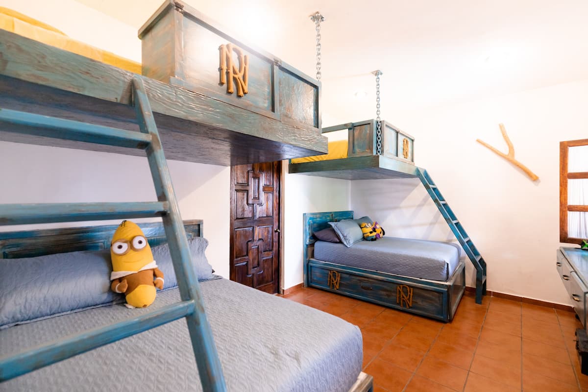 Habitación con literas, una escalera, un juguete pequeño y una puerta de madera.