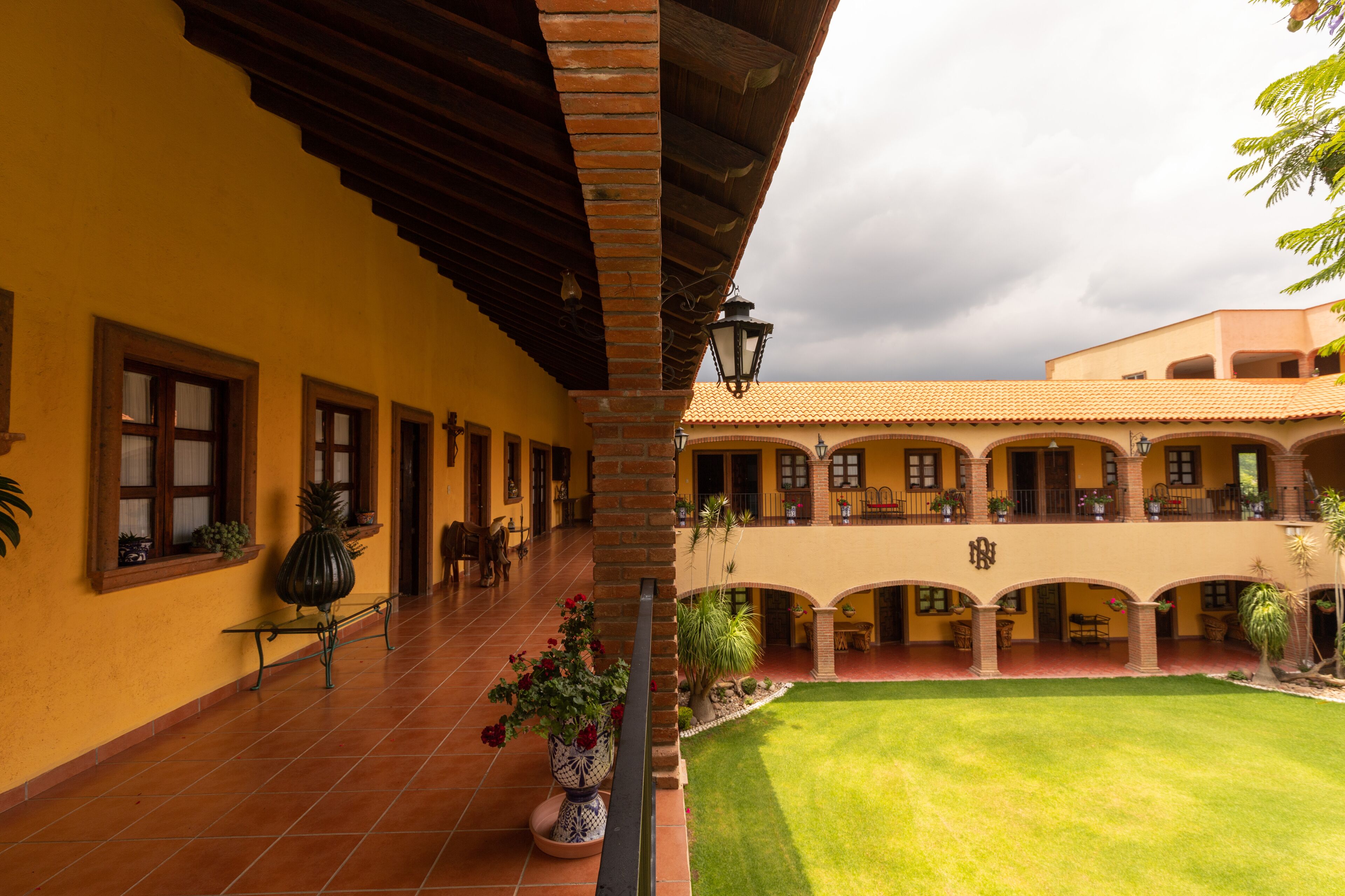 Un patio con suelo de baldosas, un corredor cubierto y un edificio con varios balcones y ventanas.