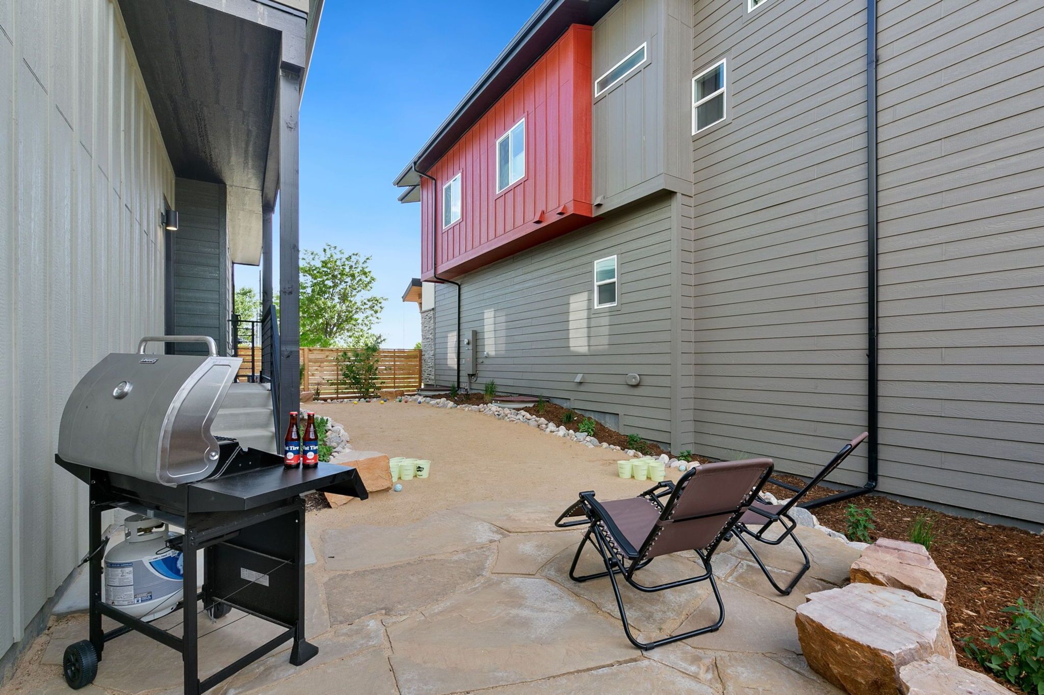 A patio with a barbecue grill, outdoor seating, and a stone pathway.