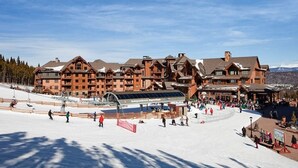 Une station de ski dotée d’un grand chalet comprenant plusieurs étages et d’une zone dédiée aux remontées mécaniques.