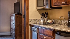 Une cuisine équipée de meubles en bois, d’un four à micro-ondes, d’une bouilloire et d’un lave-vaisselle.