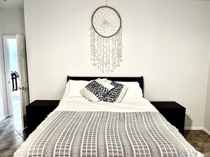 A bedroom with a bed, a dreamcatcher, and a patterned bedspread. - Hillside Desert House - Hot Tub, Fire Pit And Bbq! 3 Bedroom Home by RedAwning (Yucca Valley)