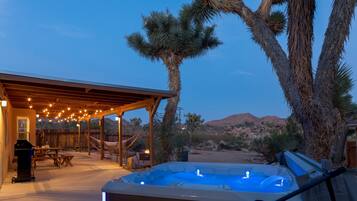 Relax in a tranquil outdoor space with a hot tub, dining area, and hammock, perfect for unwinding in a warm desert climate.