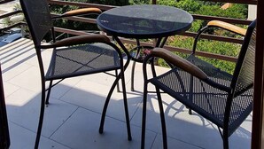A balcony with a table and chairs overlooking a body of water and distant islands. - Apartment Stella (Zupa dubrovacka)