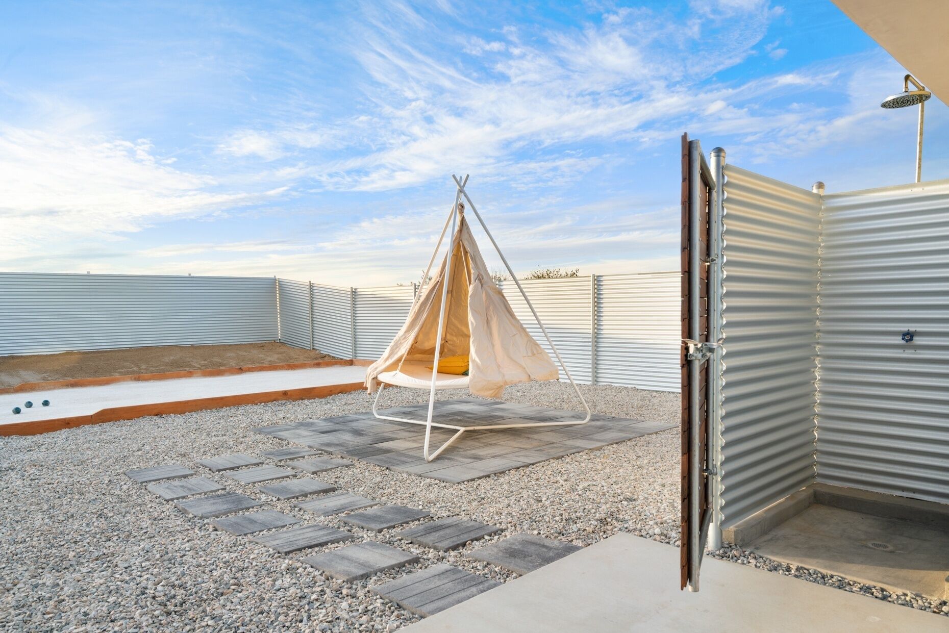 A rooftop terrace with a hanging swing chair, a small pool, and a metal gate.