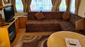 A cozy living area with a sofa, a television, and a coffee table. - Caravan for Rent Coral Beach R2v7 Ingoldmells (Skegness)