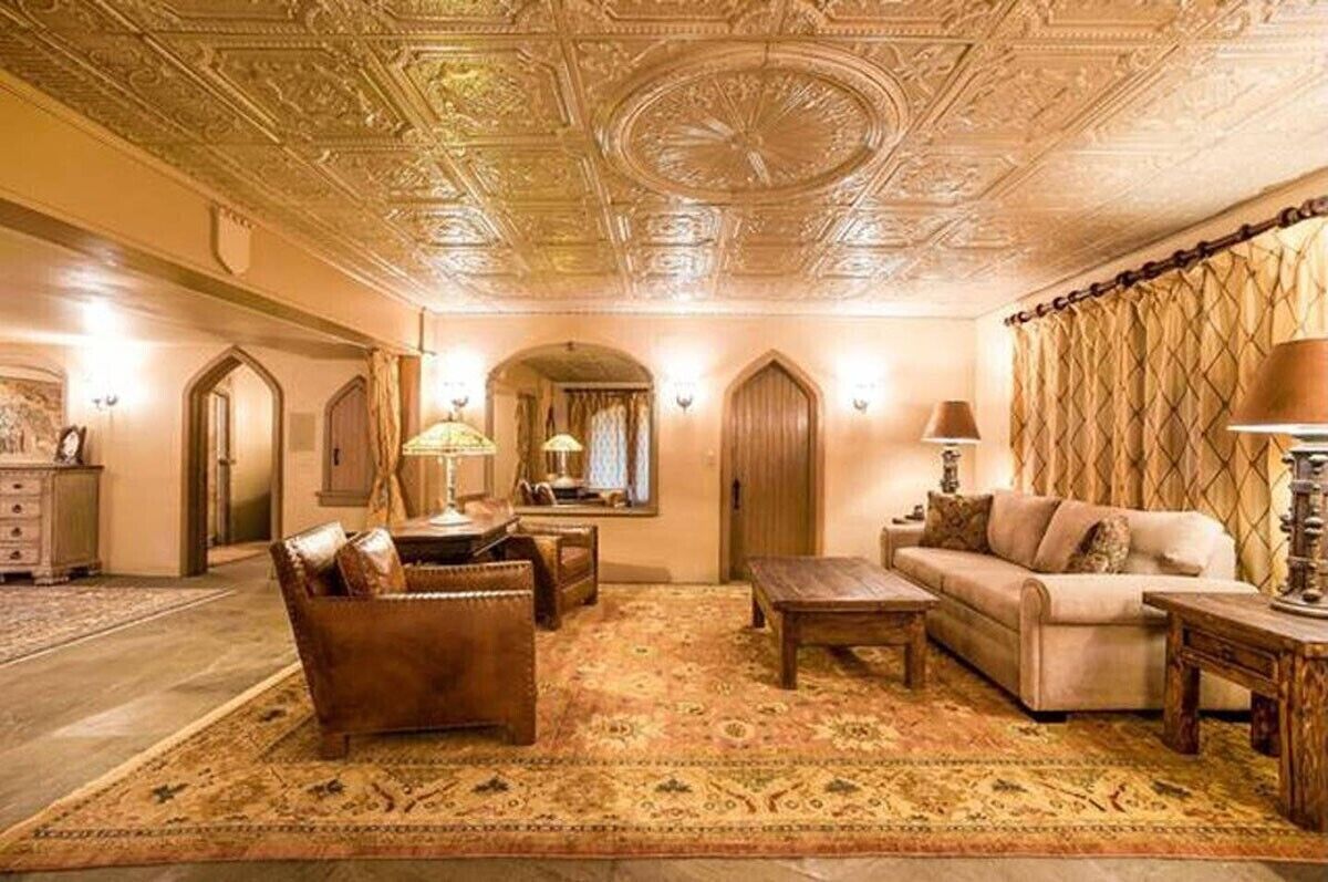 A luxurious room with ornate ceiling, a plush sofa, a wooden coffee table, and a patterned rug.