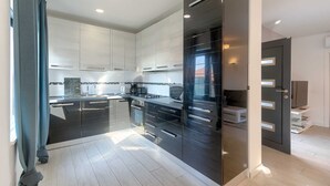 Une cuisine moderne dotée de meubles aux lignes épurées, d’un îlot central et d’appareils électroménagers intégrés.