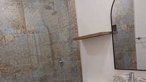 Een badkamer met douche, toilet en wastafel.