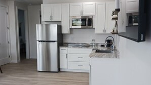 Een moderne keuken met witte kasten, roestvrijstalen apparatuur en een marmeren aanrecht.