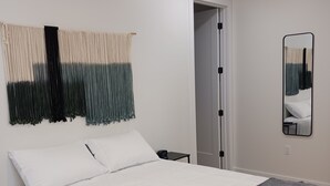 Een slaapkamer met een bed, een plafondventilator, een spiegel aan de muur en een deur.