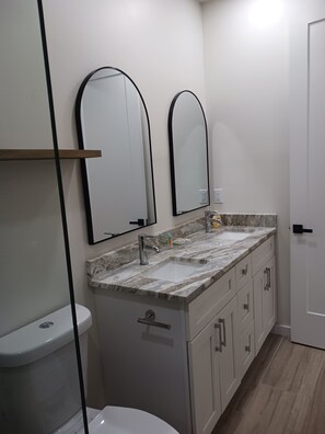 A bathroom with a toilet, a sink with a marble countertop, and two wall-mounted mirrors.