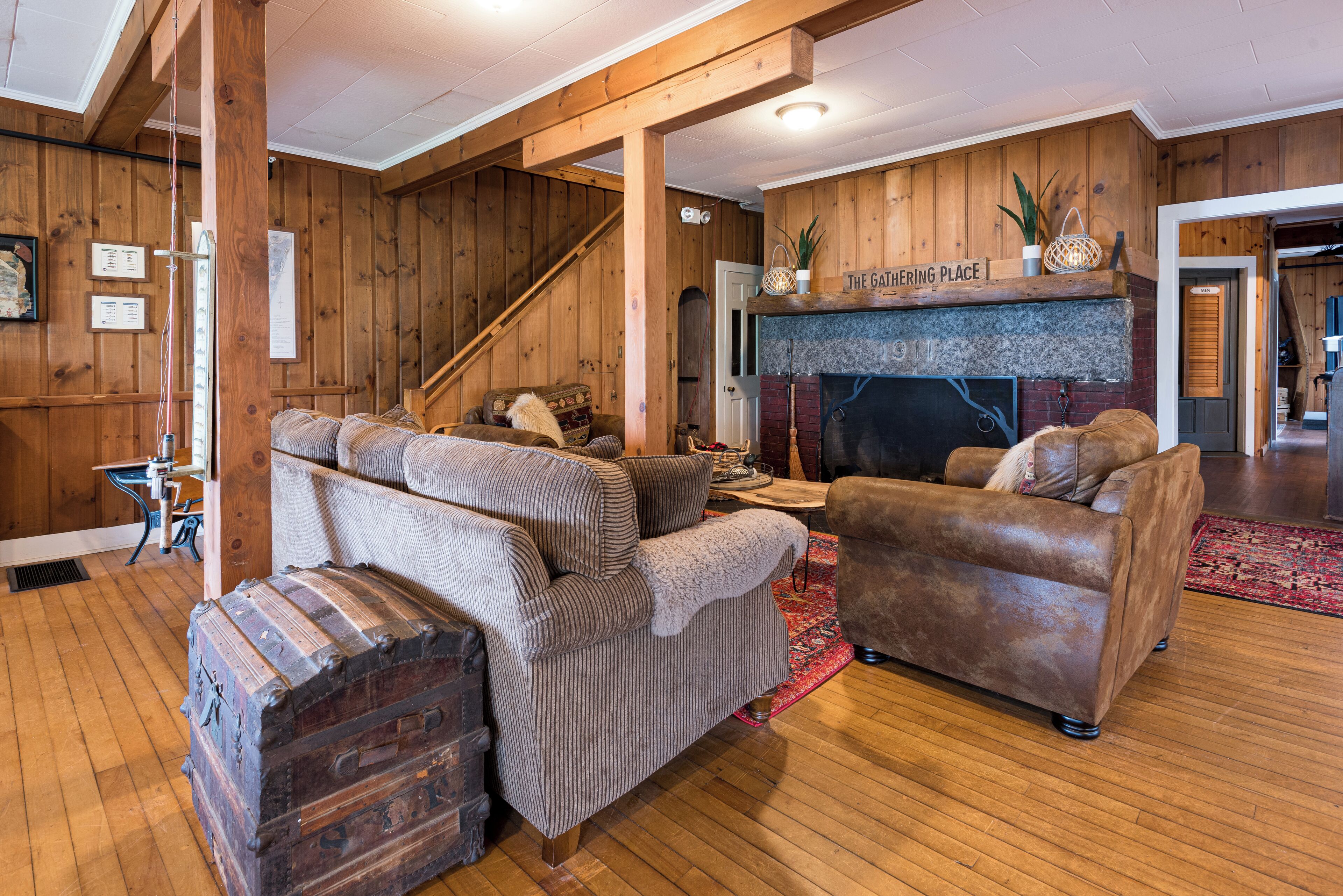 Un salon chaleureux avec des murs en bois, une cheminée et un escalier.