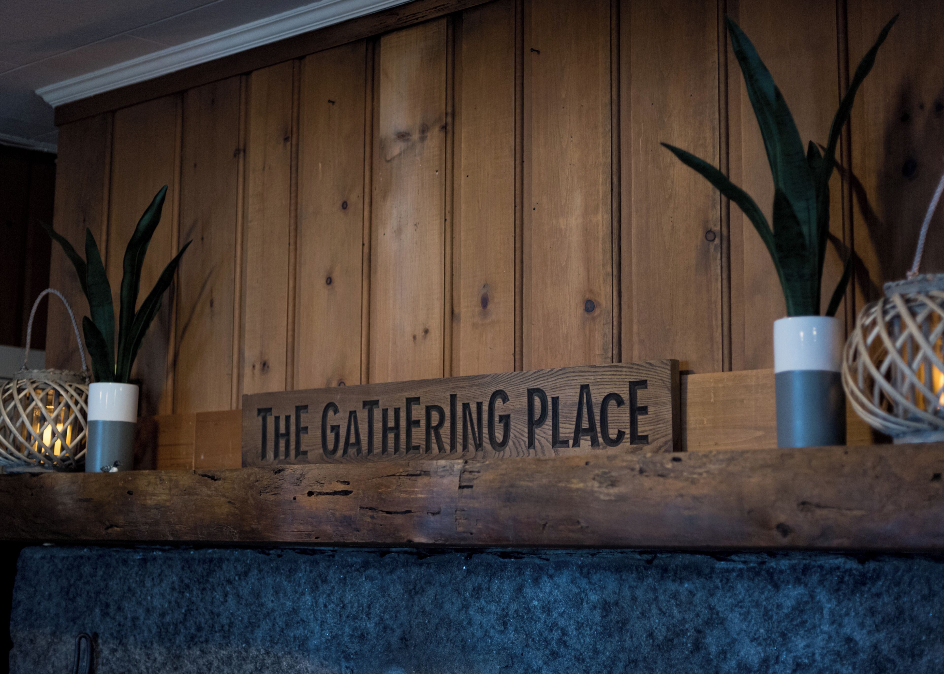 A wooden sign with the text "The Gathering Place" on a stone ledge.